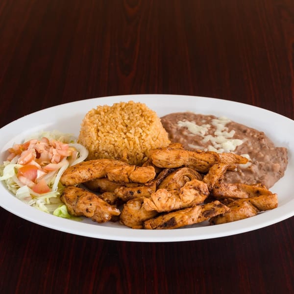 Grilled chicken strips, Spanish rice, refried beans with cheese, and a side salad on a white plate.